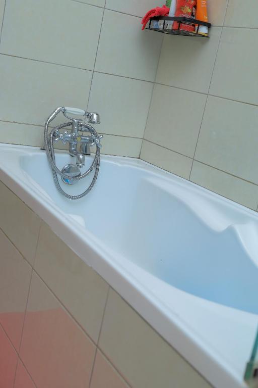 a bath tub with a faucet on top of it at Cozy Retreat in Kampala