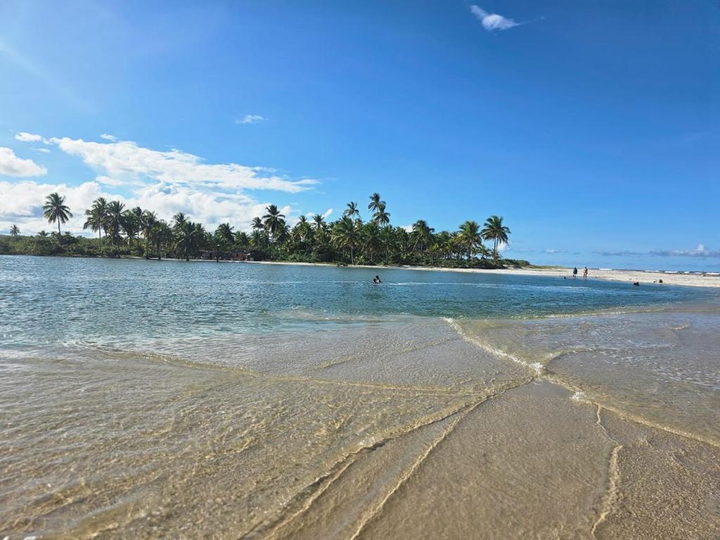 a beach with a group of people in the water at Pérola Rosa 04 in Ilhéus