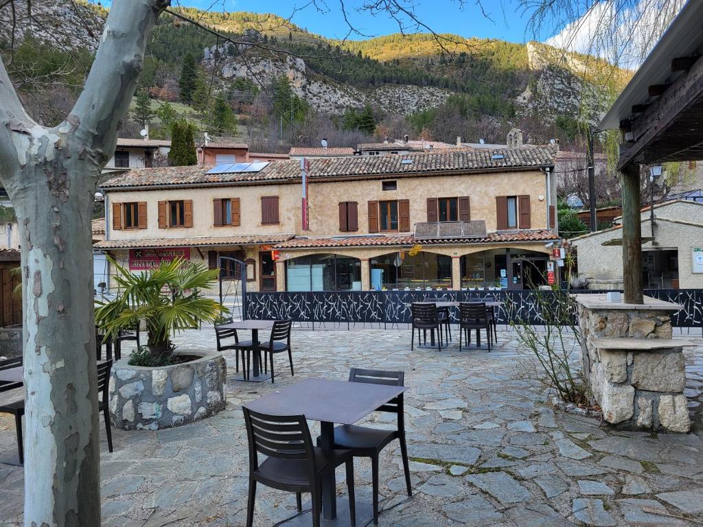 a patio with tables and chairs in front of a building at RELAIS du BECASSIER in Annot