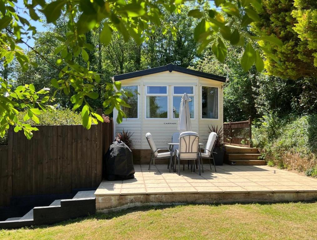 a patio with a table and chairs and a house at Devon Tor View Country Retreat in Bratton Clovelly