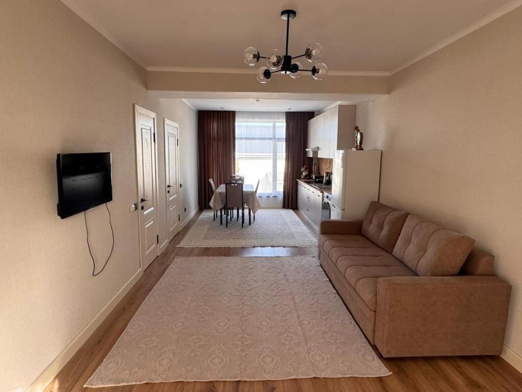 a living room with a brown couch and a kitchen at Karagay resort in Bosteri
