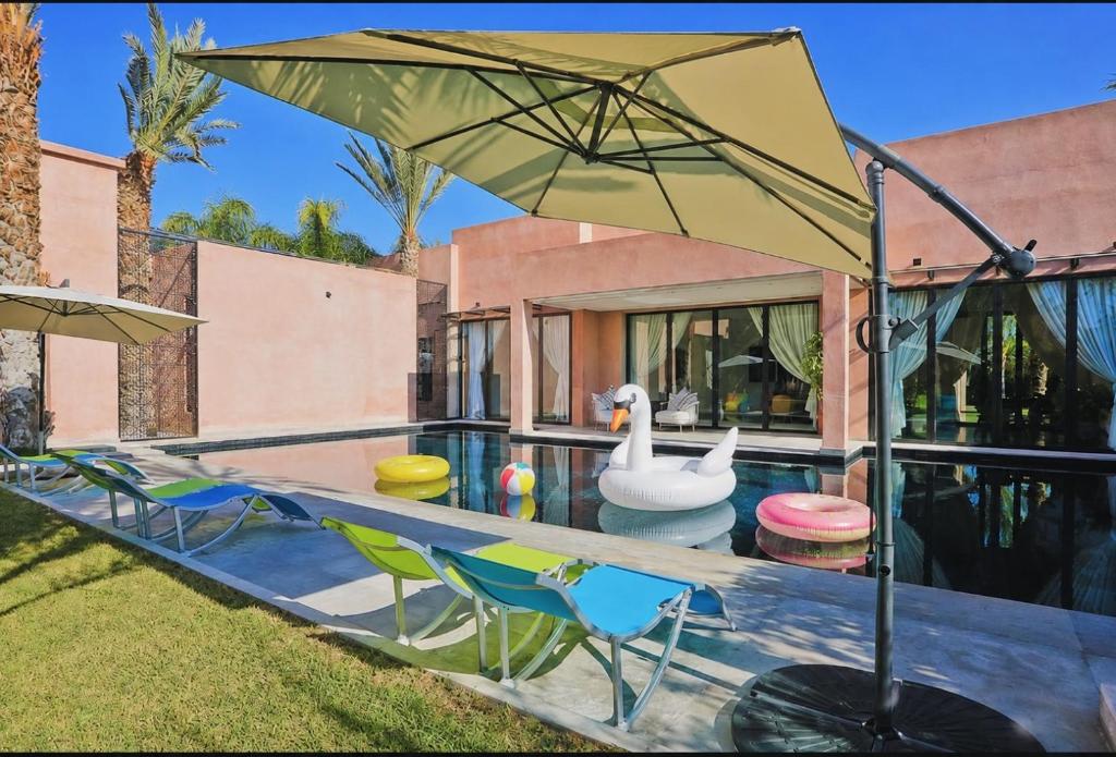 a house with a pool with chairs and an umbrella at Luxury Marrakech Villa marrakech pool,staff,brekfast included in Marrakesh