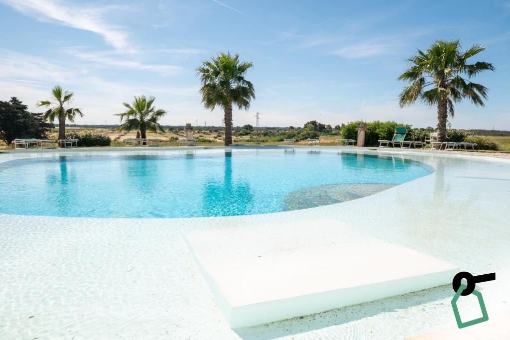 a large swimming pool with palm trees in the background at Hotiday Torre Guaceto in Brindisi