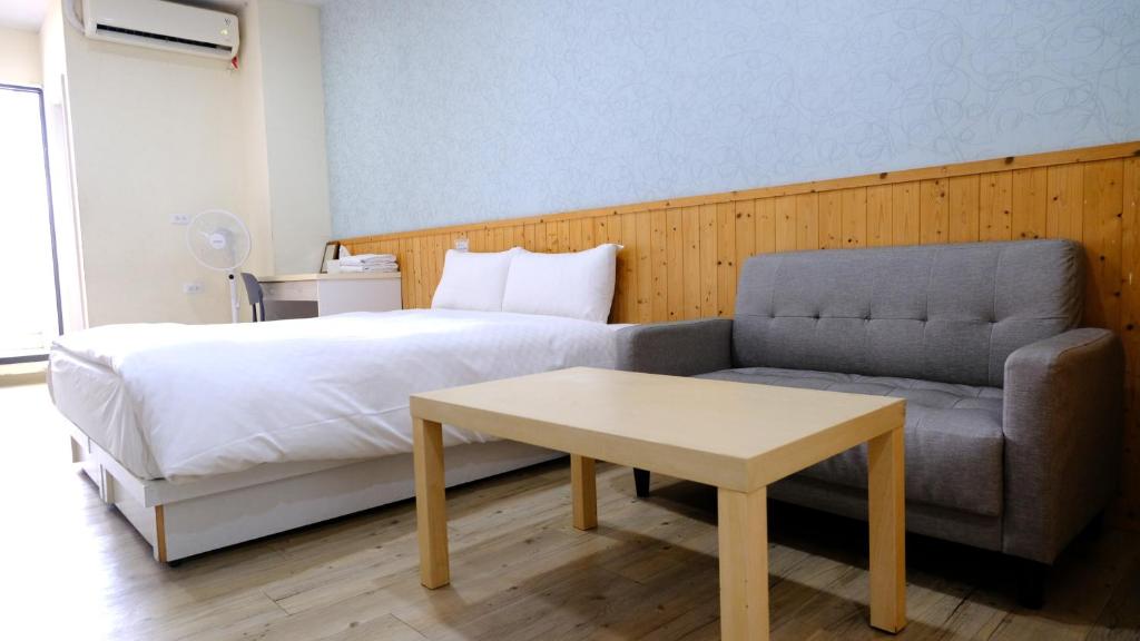 a bedroom with a bed and a couch and a table at Didi House無人化自助入住 in Tainan