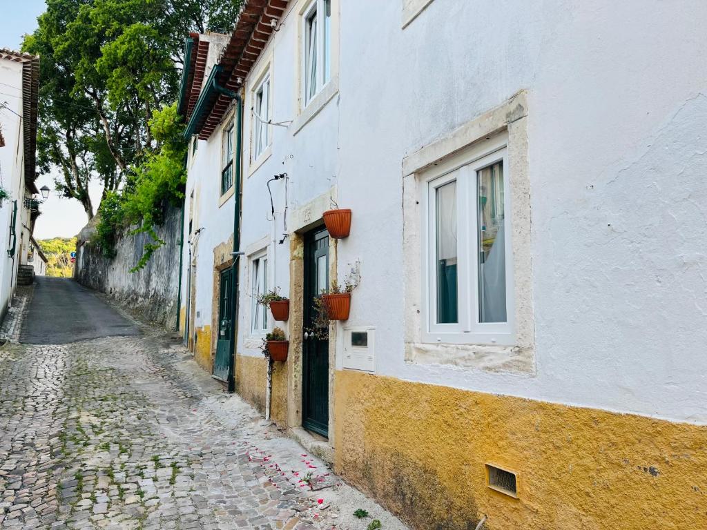 an alley with a white building and a window at Pé do Castelo Casinhas in Tomar