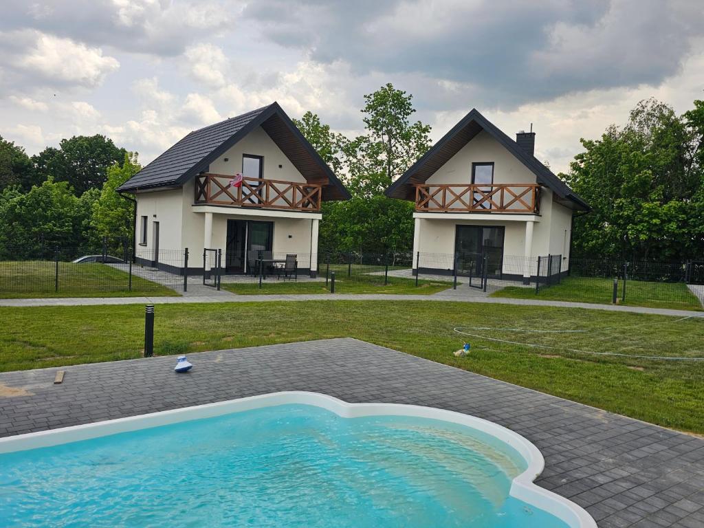a house with a swimming pool in front of a house at Mazurska Osada in Januszkowo