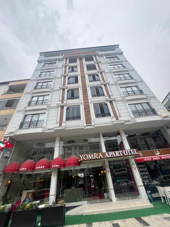 a tall building with red umbrellas in front of it at yomra apart otel in Yomra