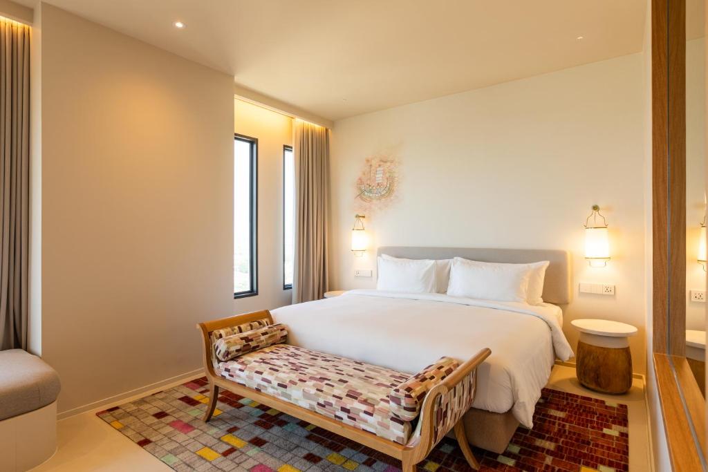 a bedroom with a large white bed and a bench at Centara Ayutthaya in Phra Nakhon Si Ayutthaya