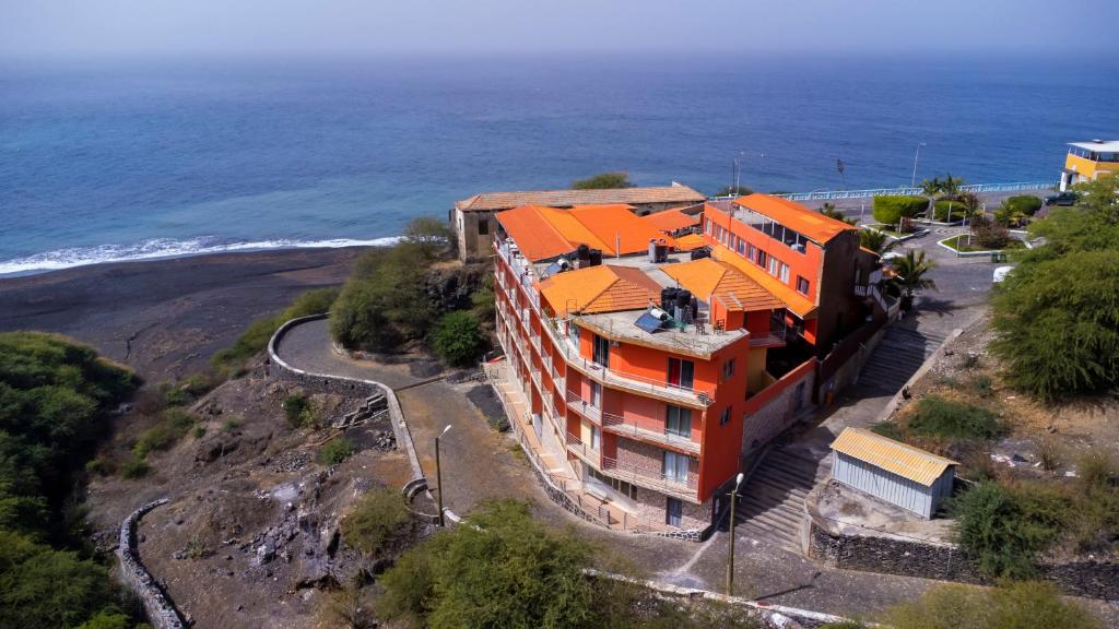 an orange building on a hill next to the ocean at Hotel Ocean View & Restaurante Seafood in São Filipe