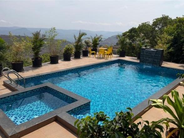 a large pool with blue water in a yard at Navishka'S Villa in Panchgani