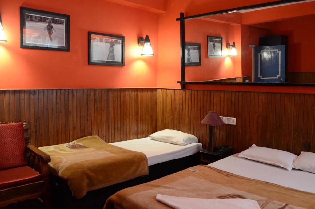 a hotel room with two beds and a mirror at Hotel Kalika Darjeeling in Darjeeling