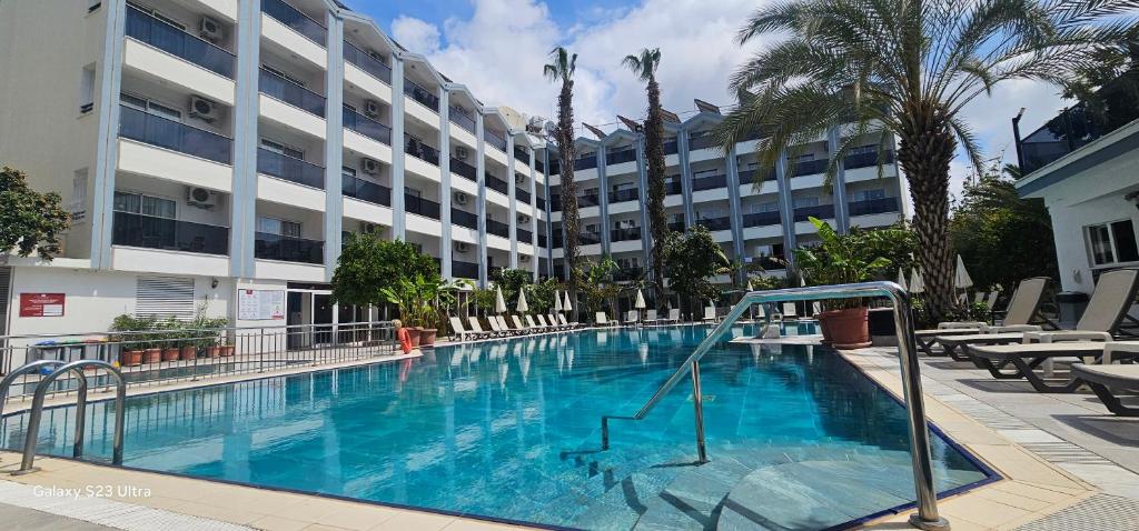 a large swimming pool with chairs and a building at Gazipasa Star Otel in Side