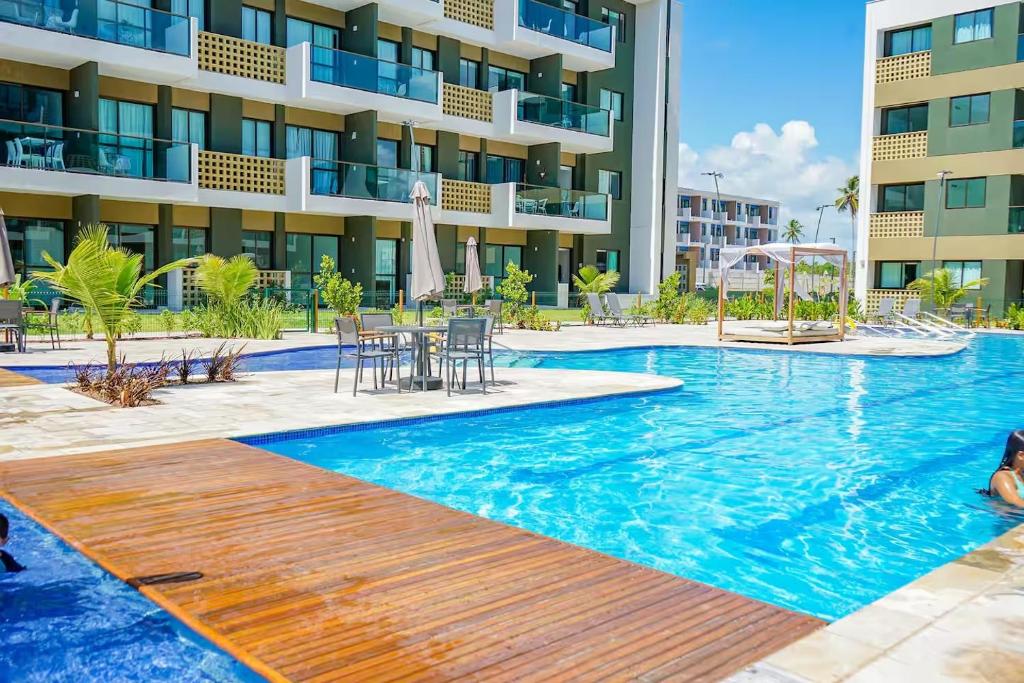 a swimming pool with tables and chairs and a building at Resort Mana Beach Experience By Beachflatsporto in Porto De Galinhas