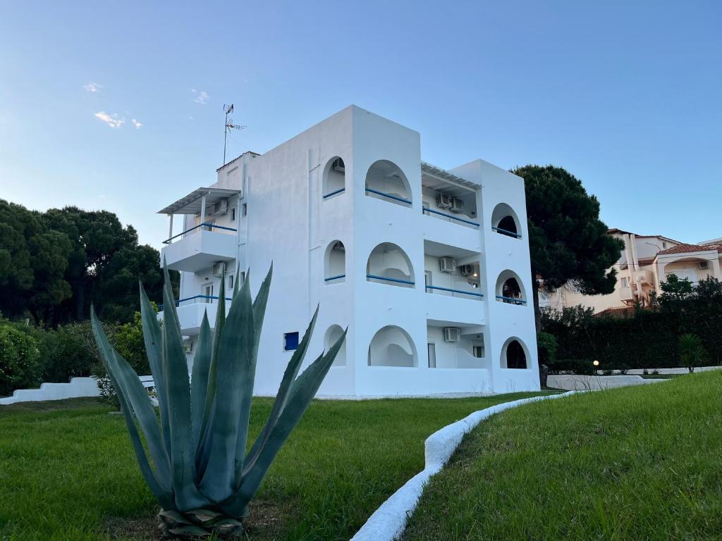 a white building with a plant in front of it at Maistrali Studios Skiathos in Koukounaries