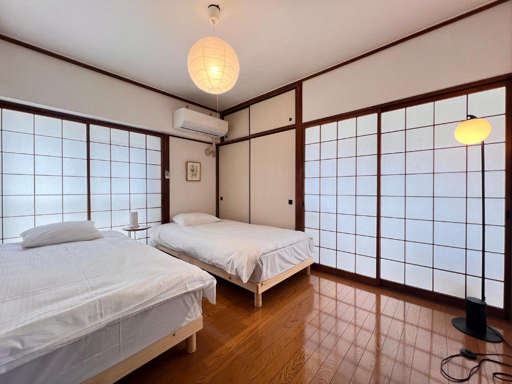 two beds in a room with large windows at 北浜 港近くの個室ステイ in Takamatsu