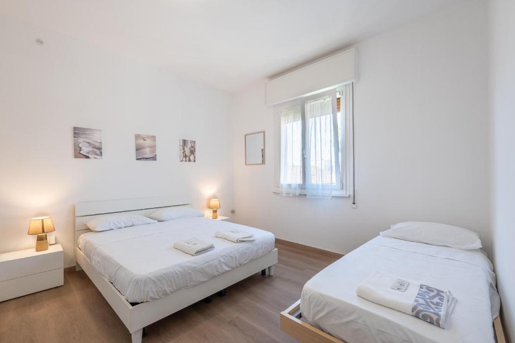 a white bedroom with two beds and a window at Due passi dal mare - Residence Sirena in Punta Marina
