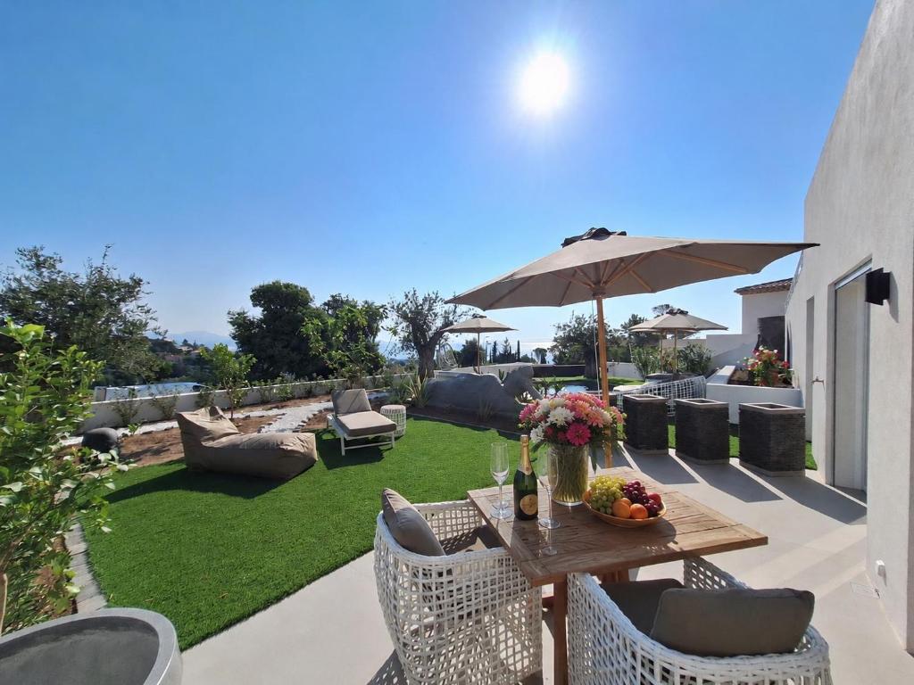 a patio with a table and chairs and an umbrella at Appartements vue mer Rêves d'Azur Les Issambres in Les Issambres