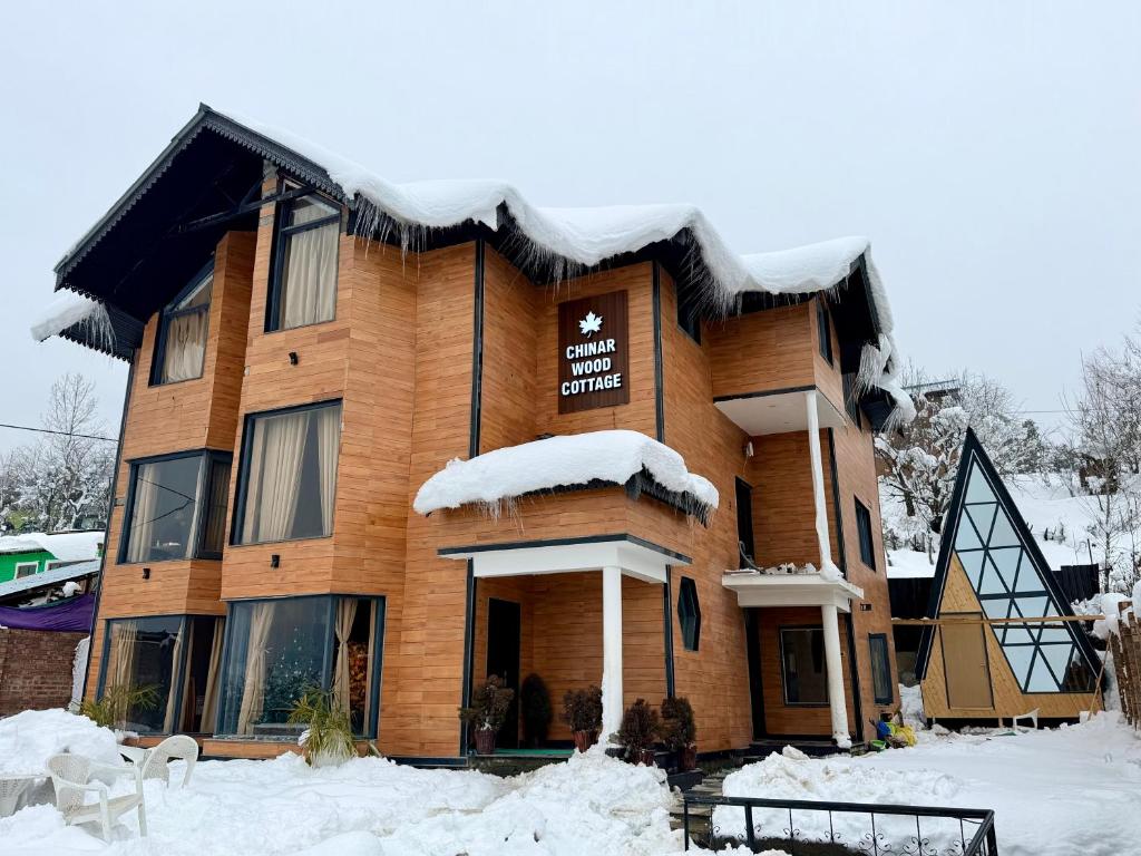 a large wooden building with snow on the ground at Chinar Wood Cottage in Gulmarg