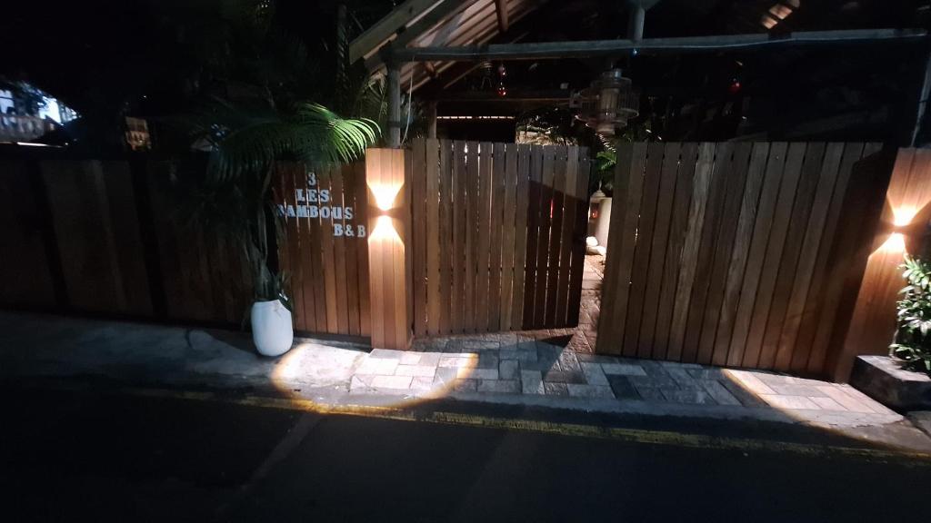 a wooden fence with a gate with a palm tree at Residence Les Bambous in Mahébourg