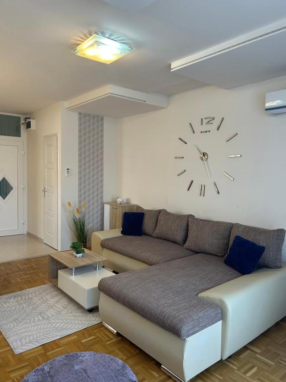 a living room with a couch and a clock on the wall at László Apartman in Debrecen