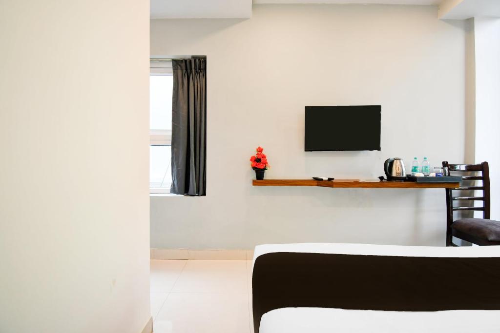 a living room with a television on a white wall at Super Townhouse Sayhallo Narcos in Bhubaneshwar