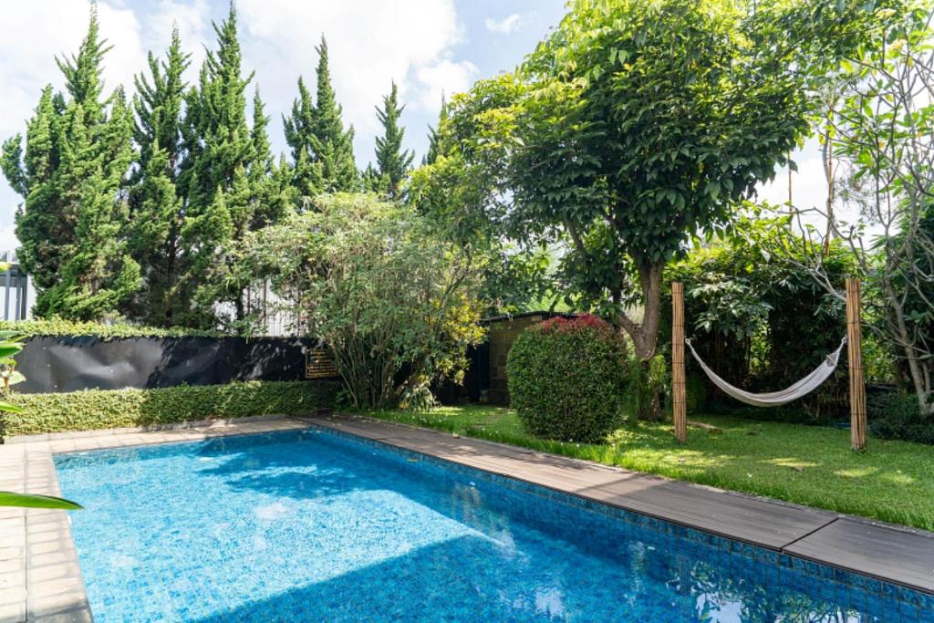 a swimming pool in a yard with trees at Breeze Blows City View Villa 4 Bedrooms and 1 Familly Bedroom With a Private Heated Swimming Pool and a Billiard Table in Bandung