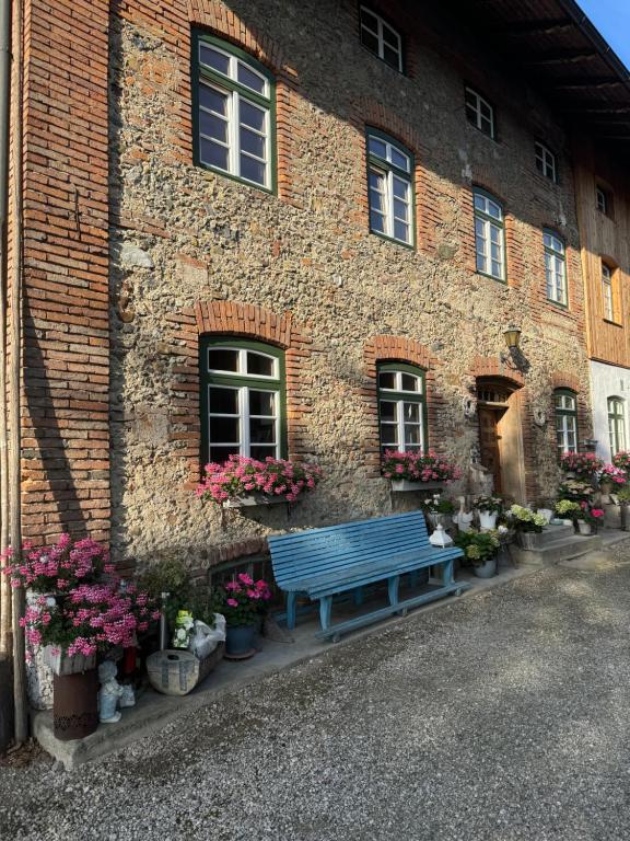 a blue bench in front of a brick building with flowers at falternhof apartment - geschichte trifft auf design in Höslwang