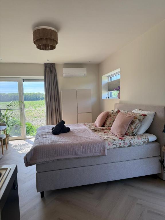 a bedroom with a large bed and a large window at B&B Bos en Dal in Blesdijke