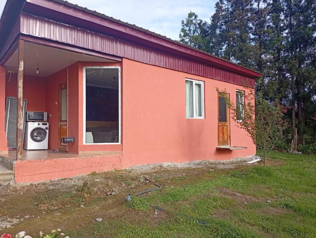a small red house with a washing machine in front of it at Nika's Home in Ureki