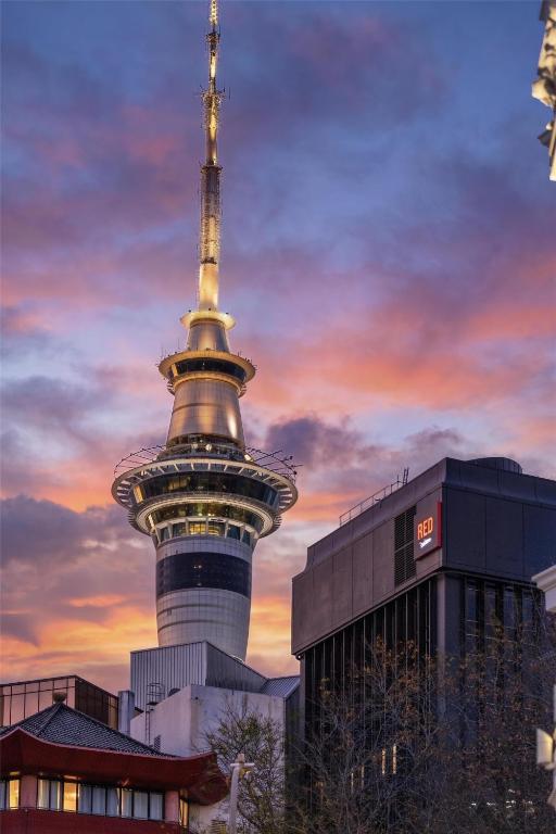 a tv tower in front of a building with a sunset at Radisson RED Auckland in Auckland
