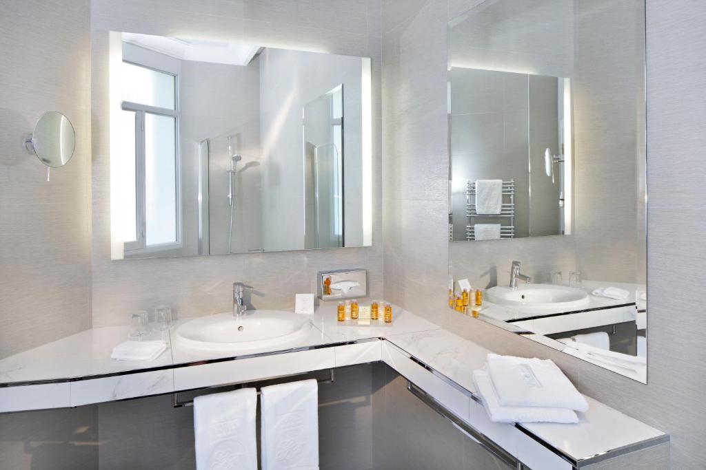 uma casa de banho com dois lavatórios e dois espelhos em Hôtel Château Frontenac em Paris