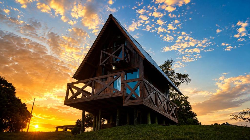 a house on a hill with a sunset in the background at Chalés Recanto da Serra in Bocaina do Sul