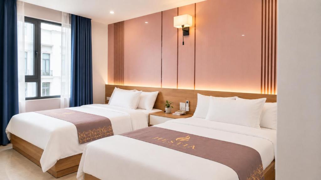 a hotel room with two beds and a window at Hestia Hotel Móng Cái in Móng Cái