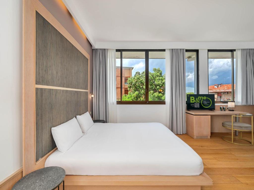 a bedroom with a bed and a desk and windows at B&B HOTEL Padova Methis in Padova