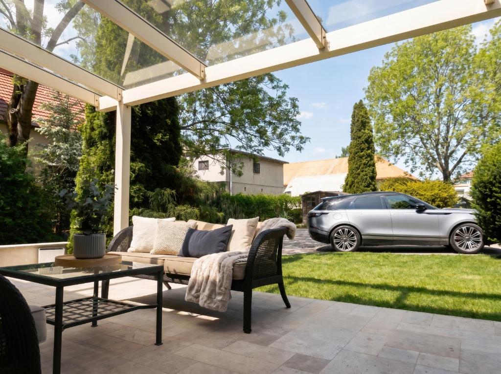 a patio with a couch and a table and a car at Golden Villa Kraków - Stylowa Willa z Ogrodem i Grillem in Węgrzce