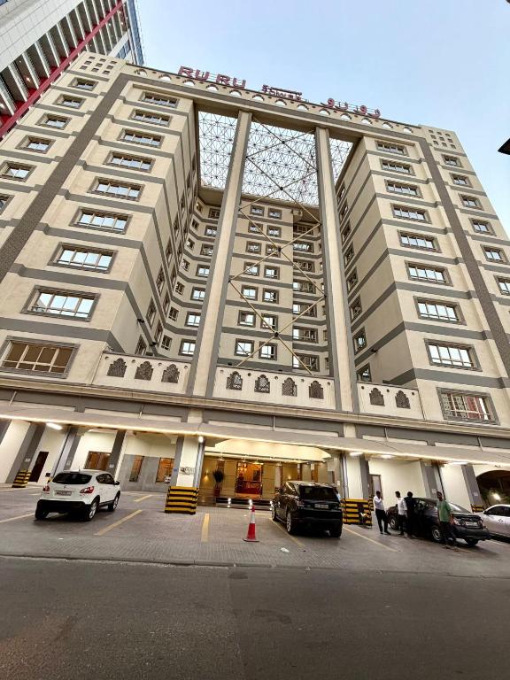 a large building with cars parked in a parking lot at Ruru Tower Luxury Apartment in Juffair