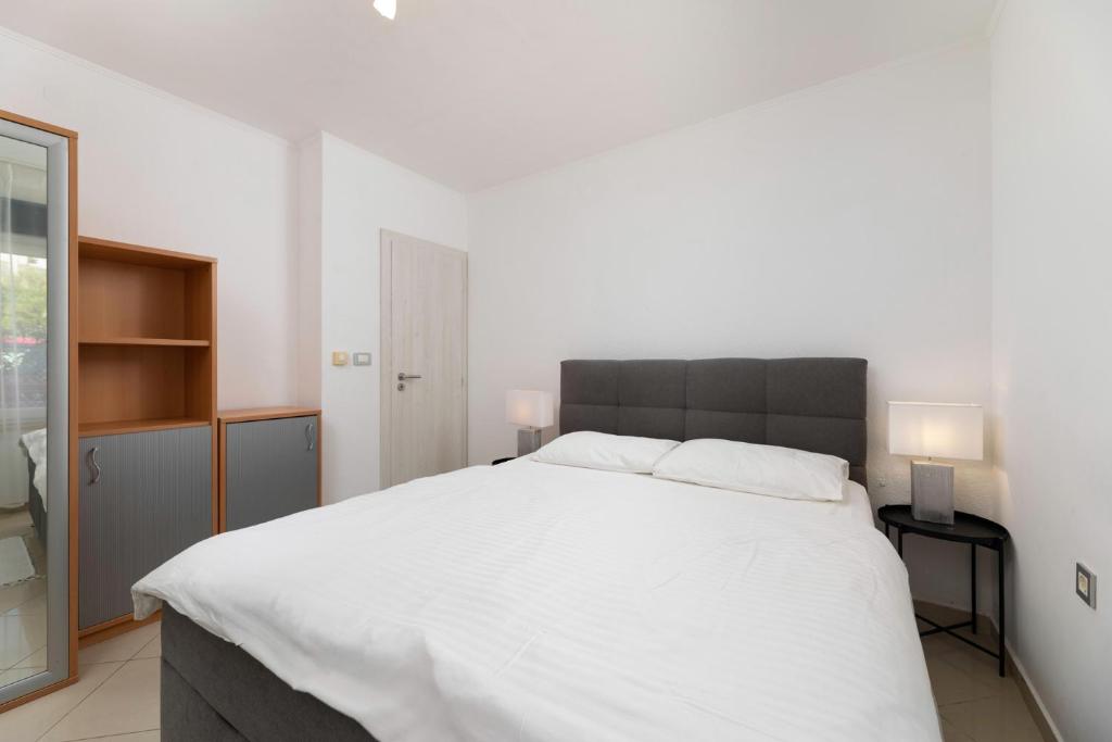 a bedroom with a large white bed with two lamps at Studio apartman Lea in Baška