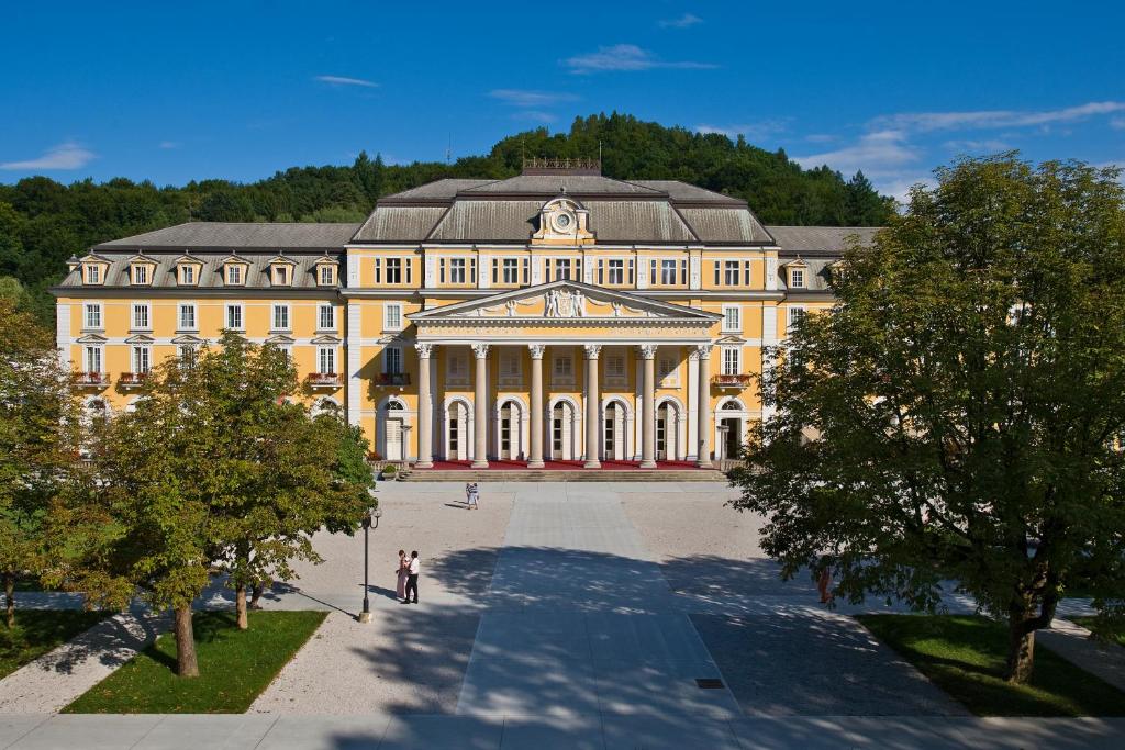 un grande edificio giallo con alberi di fronte di Grand Hotel Rogaška Premium a Rogaška Slatina