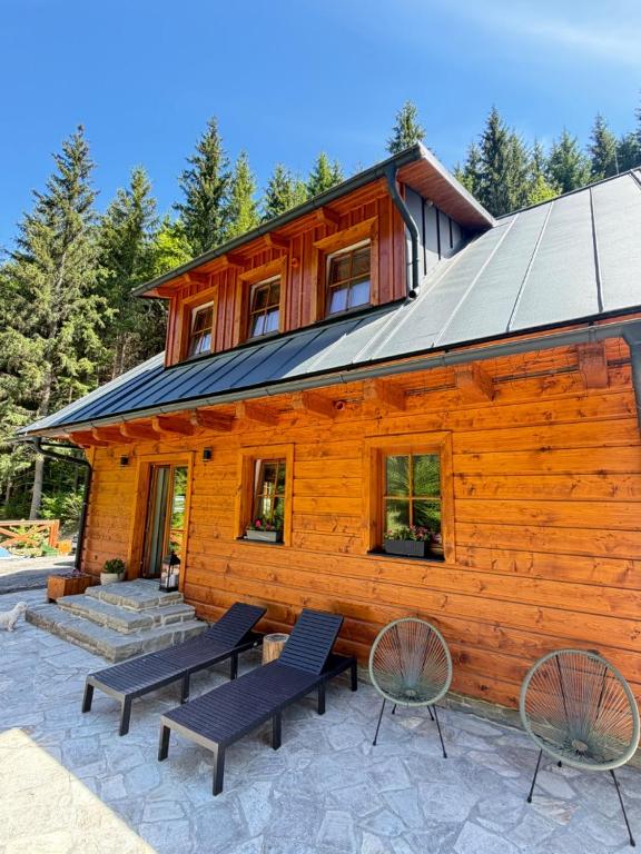 a log building with two benches and a house at Wellness Chalupa Krajanka in Nový Hrozenkov