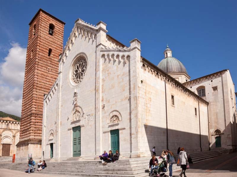 a group of people sitting on steps outside of a church at Pietrasanta Caggianelli in Pietrasanta