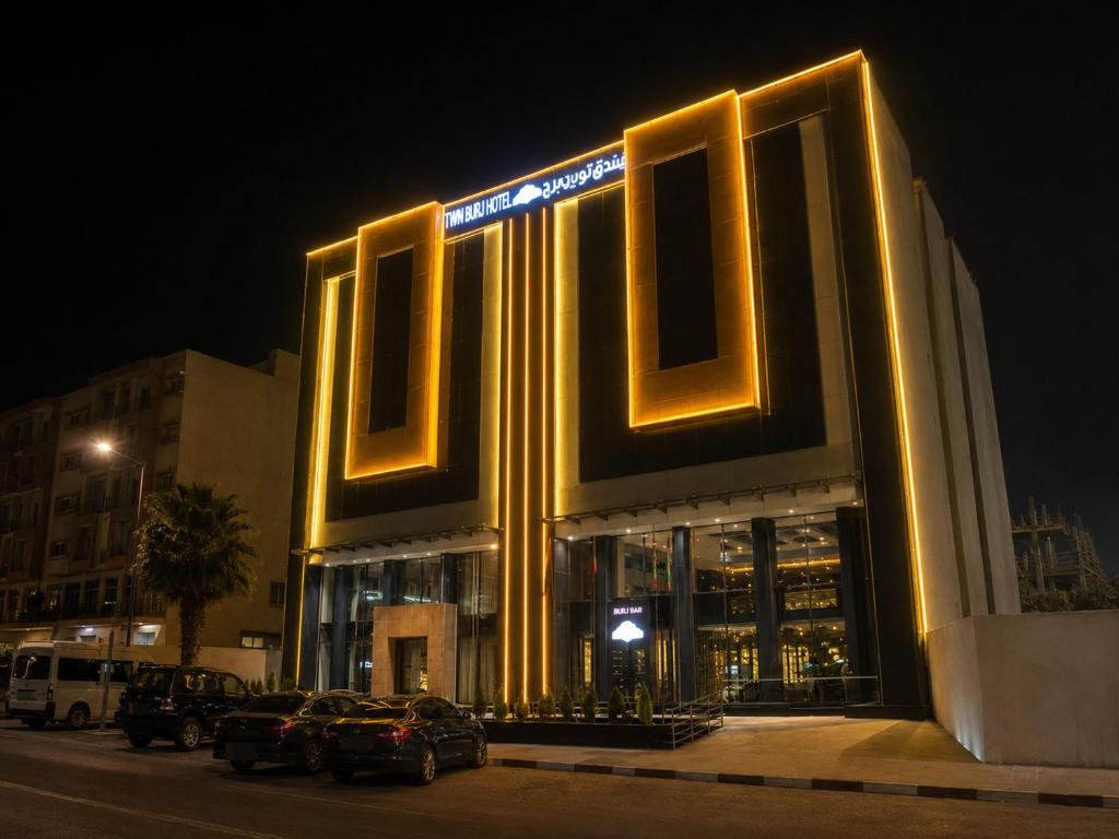 a lit up building with cars parked in front of it at Twin Burj Hotel in Nouakchott