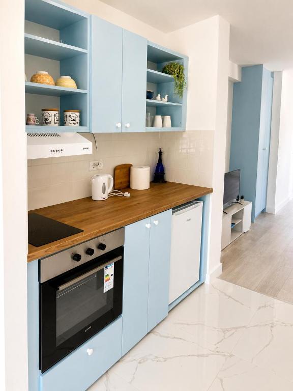 a kitchen with blue cabinets and a wooden counter top at Apartmani White House in Vrdnik