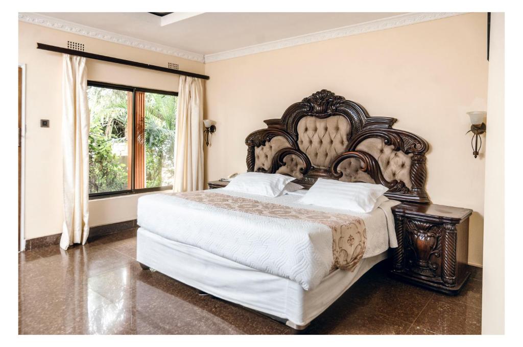 a bedroom with a large bed with a large headboard at Leon's Lodge in Choma