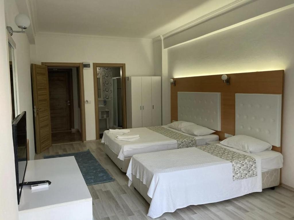 a hotel room with two beds and a flat screen tv at Uğur Otel in Kaş