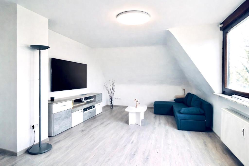 a living room with a blue couch and a tv at GEM Stay in Oberhausen