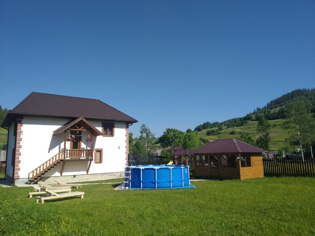 a building with two blue barrels in the grass at "Гірська Домівка" КОТЕДЖ з Чаном-Джакузі та басейном in Volosyanka