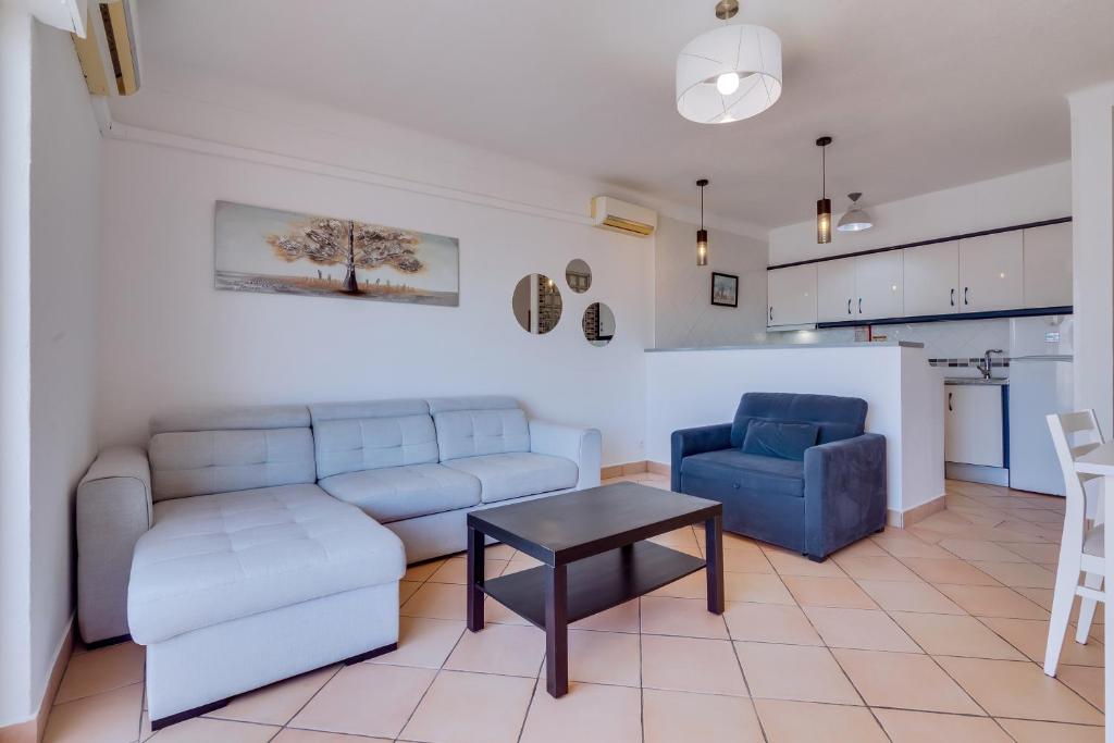 a living room with a couch and a table and a kitchen at Vale do Farol Cozy Retreat in Quarteira