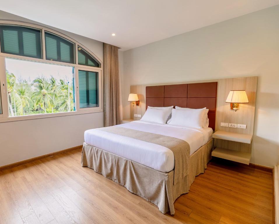 a bedroom with a large bed and a large window at Viona Beach Hotel - Marina Phu Quoc in Phú Quốc