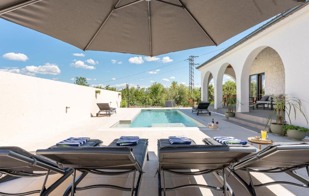 a patio with a pool and chairs and an umbrella at Villa Olivarum in Stankovci