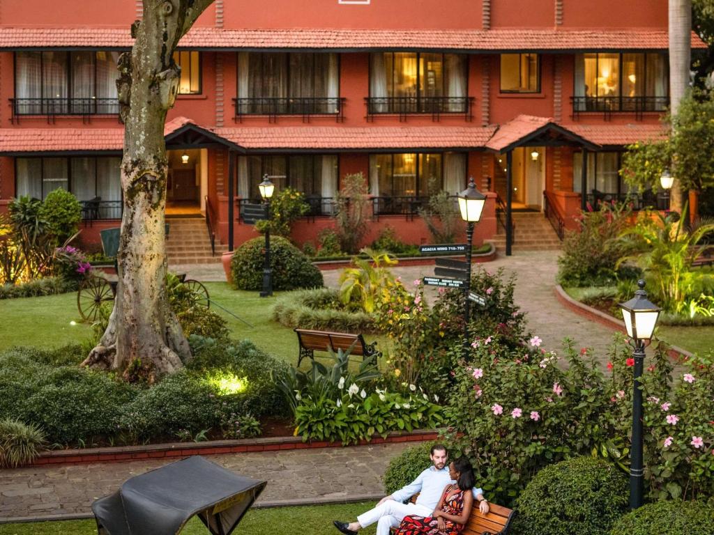 a group of people sitting on a bench in front of a building at Fairmont The Norfolk in Nairobi